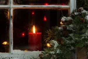 red Christmas candle in the window with Christmas tree