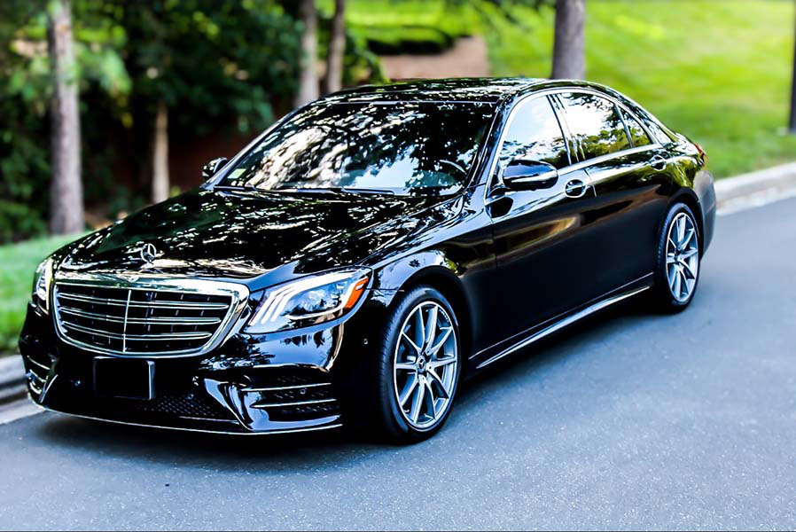 black mercedes benz on tree-lined street