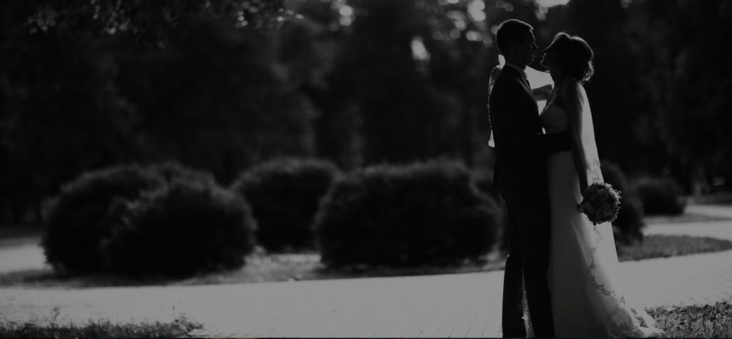 black and white photo of a bride and groom looking at each other in a park outsode
